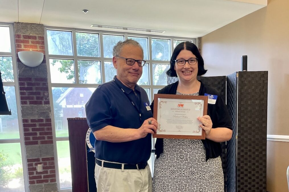 Richard Plotkin, left, receives the first Distinguished Service Award from APW President Angie Faller, right.