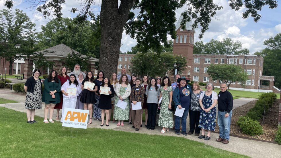 A group of Arkansas Press Women members takes a group photo in front of a tree at Central Baptist College.