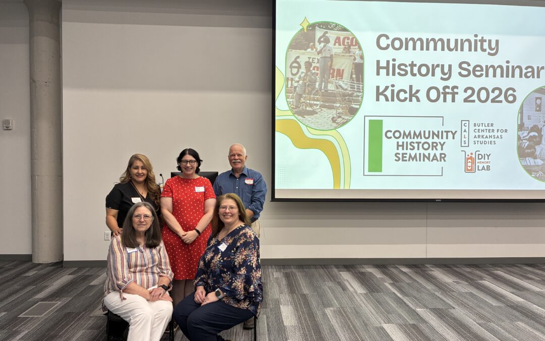 A group of people stand in front of a presentation about the Community History Seminar.